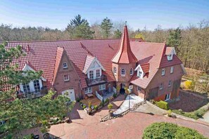 A large, multi-story building with a red-tiled roof and a prominent central tower. - Apartment "Flounder" (ID 344) - Friesenresidence (Sankt Peter-Ording)