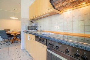 A modern kitchen with a microwave, sink, and stove. - Apartment 3B (ID 085), Germany (Sankt Peter-Ording)