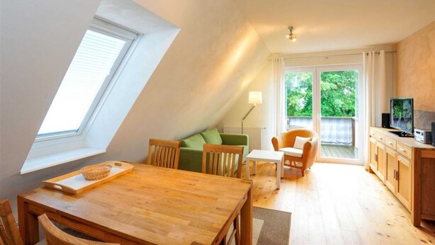 Un appartement-loft confortable avec un coin repas, un canapé, une télévision et une grande fenêtre.