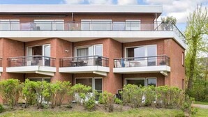 A modern multi-story building with three balconies, each with a glass railing and a door. - Apartment 23 (ID 031), Germany (Sankt Peter-Ording)