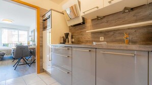 Une cuisine moderne avec des meubles gris, un pare-feu en bois et une machine à café posée sur le plan de travail.