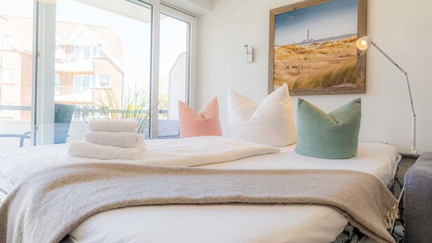 Une chambre d’hôtel avec un lit, des oreillers, une lampe et un tableau au mur.