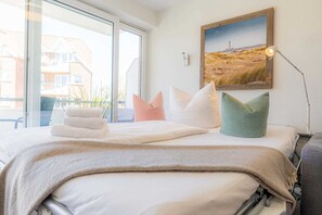 Une chambre d’hôtel avec un lit, des oreillers, une lampe et un tableau au mur.