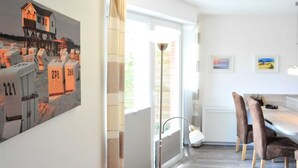 Un intérieur moderne avec un coin repas, une grande fenêtre et un tableau au mur.