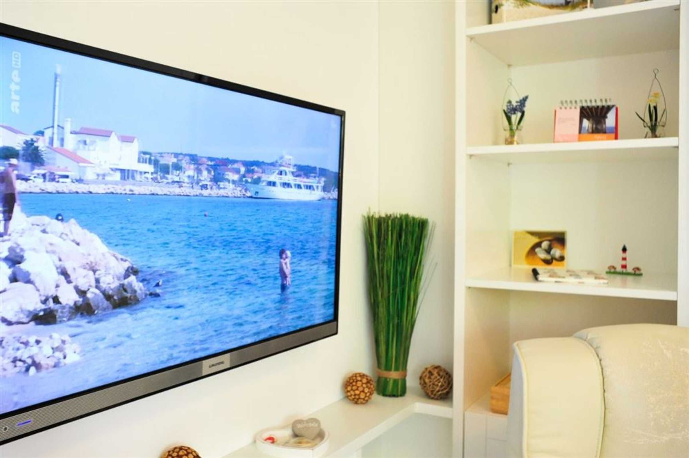 Ein Flachbildfernseher an der Wand, der eine Küstenlandschaft zeigt.