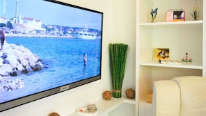 Un téléviseur à écran plat fixé au mur, diffusant une image d’un paysage côtier.