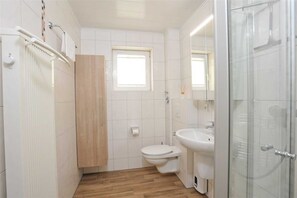 A modern bathroom with a toilet, sink, and shower. - Apartment 3 (ID 095), Germany (Sankt Peter-Ording)