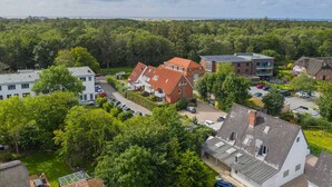 Un quartier résidentiel avec des maisons, un parking et une zone boisée en arrière-plan.