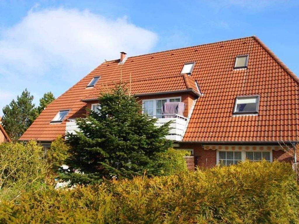 A two-story house with a red-tiled roof, multiple windows, and a chimney.