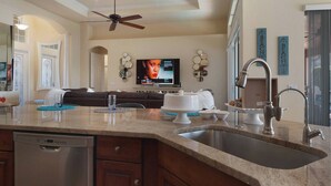 Una cocina moderna con encimera de granito, pileta de acero inoxidable y ventilador de techo.