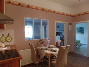 Ein Essbereich mit Tisch für vier Personen, einem Fenster und Blick auf einen Wald.