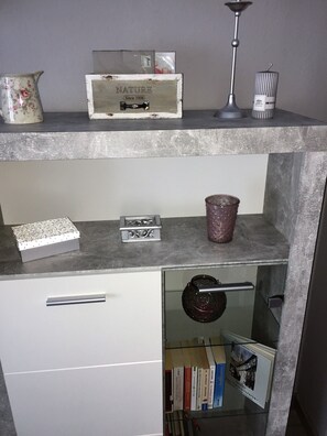 Eine Küche mit Marmorarbeitsplatte, einem weißen Schrank, einer Vitrine mit Büchern und einer dekorativen Karaffe.