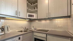 A modern kitchen with white cabinetry, a Bosch dishwasher, a microwave, and a stove.