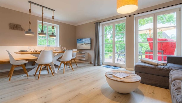 A modern living room with a dining area, large windows, and a view of the outdoors.