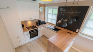 A modern kitchen with white cabinets, a wooden countertop, and a black backsplash.