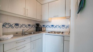 A compact kitchen with white cabinets, a stainless steel sink, and a coffee maker. - Apartment 14 (ID 212), Germany (Sankt Peter-Ording)