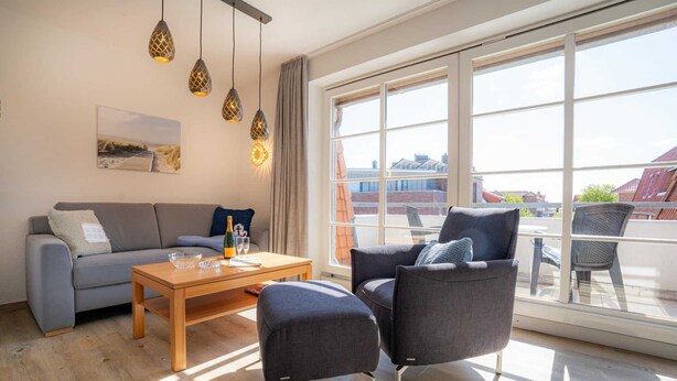 A modern living room with a sofa, two armchairs, a wooden coffee table, and pendant lights. - Apartment 14 (ID 212), Germany (Sankt Peter-Ording)