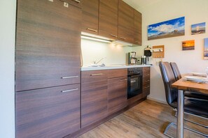 Eine moderne Küche mit dunklen Holzschränken, einem eingebauten Ofen und einem Essbereich mit Holztisch und Stühlen.