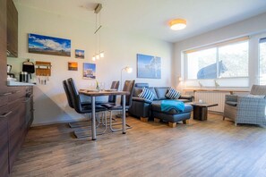 Ein modernes Wohnzimmer mit Essbereich, Holzböden und großen Fenstern.