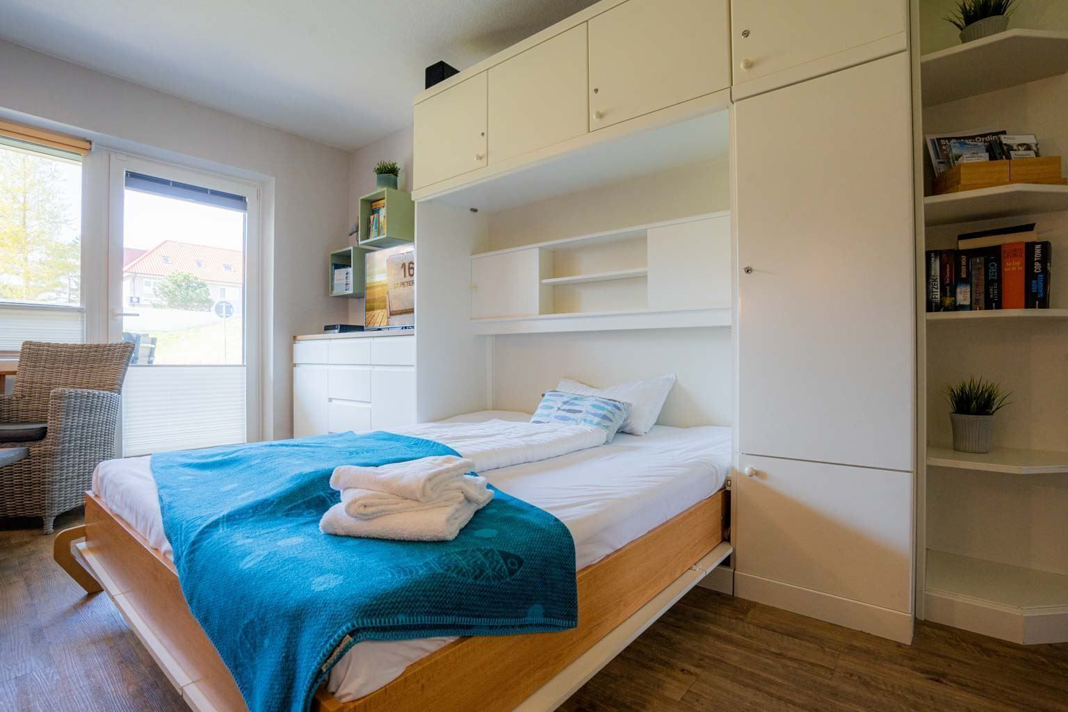 Une chambre à coucher avec un lit, une armoire, une chaise et une fenêtre.