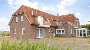 A two-story brick house with a sloped roof, large windows, and a covered outdoor area. - Apartment OG (ID 135), Germany (Sankt Peter-Ording)