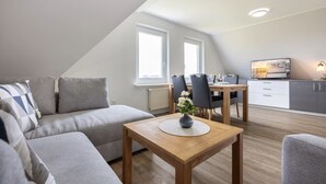 A modern loft apartment with a dining area, a sofa, and a TV. - Apartment OG (ID 135), Germany (Sankt Peter-Ording)