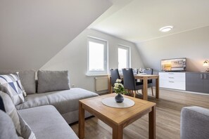 Um apartamento estilo loft moderno com sala de jantar, sofá e televisão.