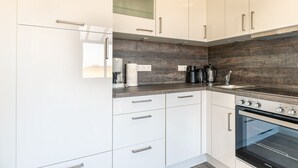 A modern kitchen with white cabinets, a dark backsplash, and stainless steel appliances. - Apartment ground floor behind (ID 136) (Sankt Peter-Ording)
