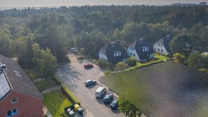 An aerial view of a residential area with houses, a parking lot, and a forested background. - Apartment OG (ID 313), Germany (Sankt Peter-Ording)