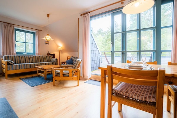 A cozy room with a sofa, chairs, a dining table, and large windows. - Apartment OG (ID 313), Germany (Sankt Peter-Ording)