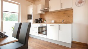 A modern kitchen with white cabinets, a wooden countertop, and a built-in oven. - Ferienhaus 1 Wolfschlucht (Prüm OT Walcherath)