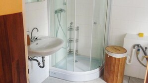 Casa de banho com cabine de duche em vidro, lavatório e sanita.
