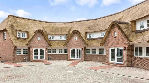 A traditional building with a curved roof and brick walls, featuring multiple windows and a courtyard. - Apartment 2 "Nordseetraum 2" (ID 059) - Haus Storchennest (Sankt Peter-Ording)