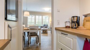 A modern kitchen with a wooden countertop, a coffee maker, and a coffee bean container. - Apartment 2 "Nordseetraum 2" (ID 059) - Haus Storchennest (Sankt Peter-Ording)