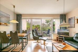 Un salon moderne comprenant un coin repas, un canapé en cuir et un téléviseur.