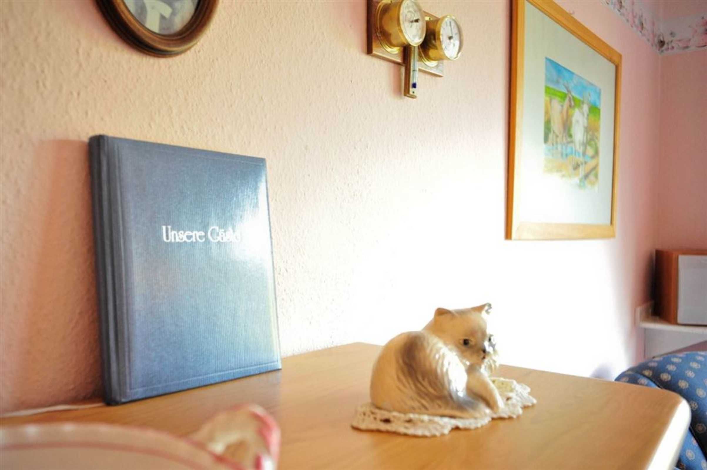 Una habitación con un libro azul titulado 'Unseen City' sobre una mesa, una figurita, un reloj de pared y un cuadro enmarcado.