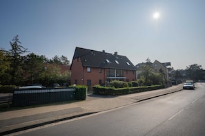 A residential street with houses, a clear sky, and parked cars.