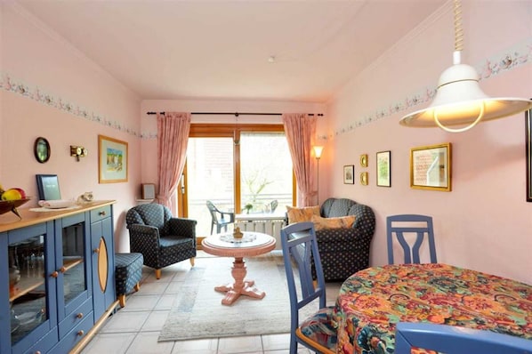 A cozy room with a dining table, chairs, a sofa, and a cabinet.