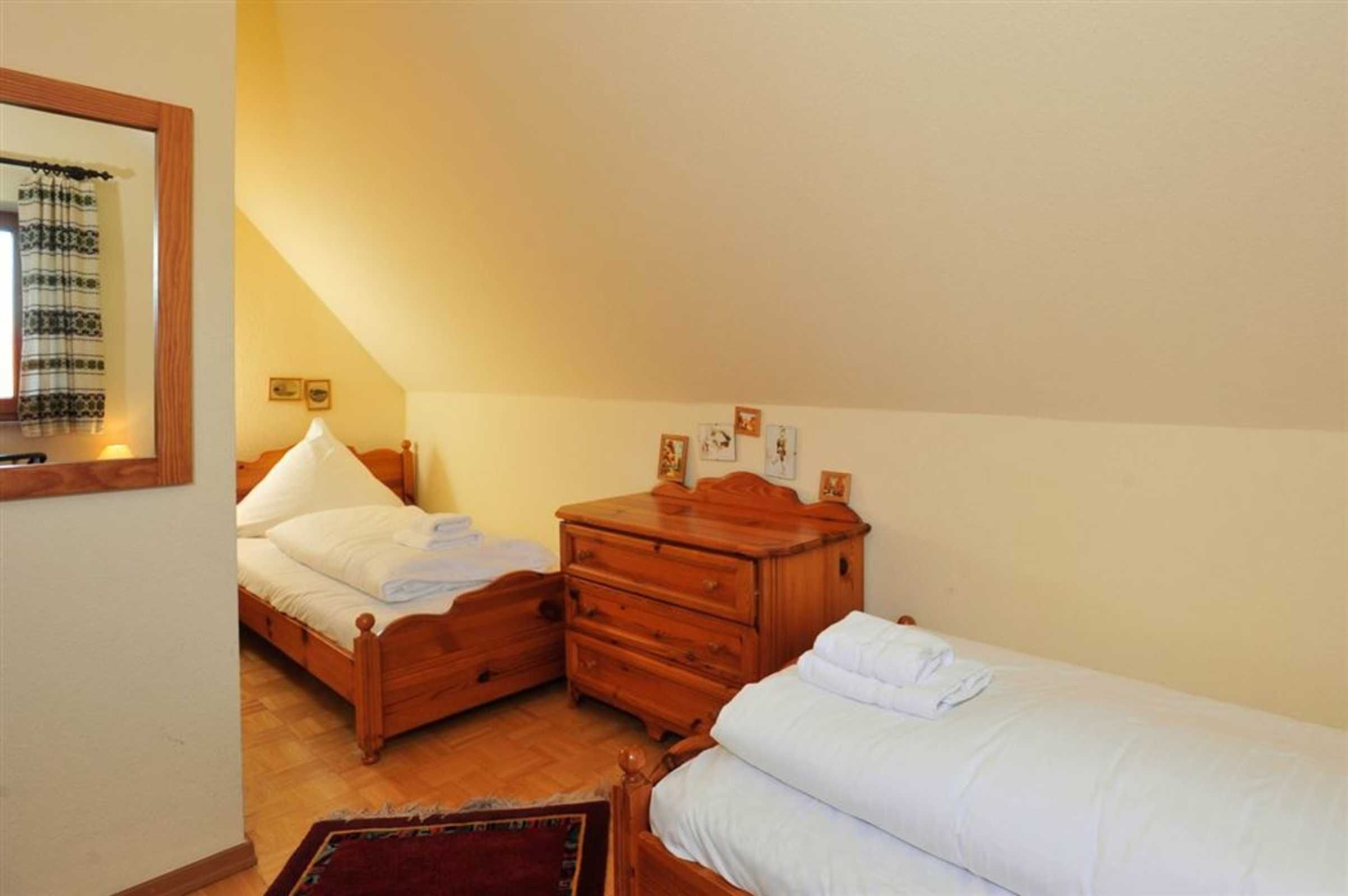 Un dormitorio con cama de madera, cómoda de madera y una mesita de noche pequeña.
