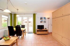 A compact living space with a dining area, a television on a wooden stand, and a wardrobe. - Apartment 2 (ID 153), Germany (Sankt Peter-Ording)