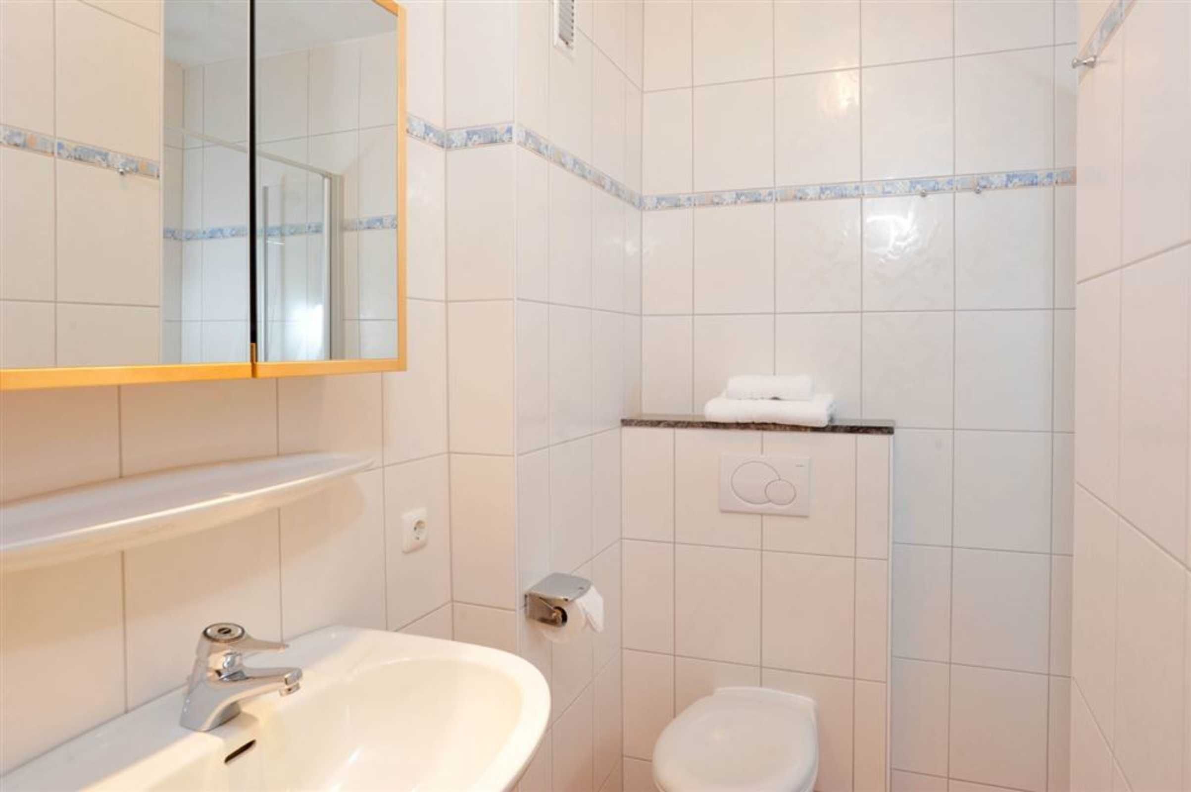 A bathroom with a white sink, mirror, and toilet.