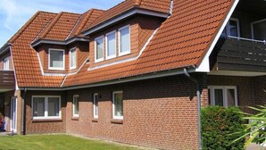 A two-story house with a sloped roof, brick exterior, and multiple windows.