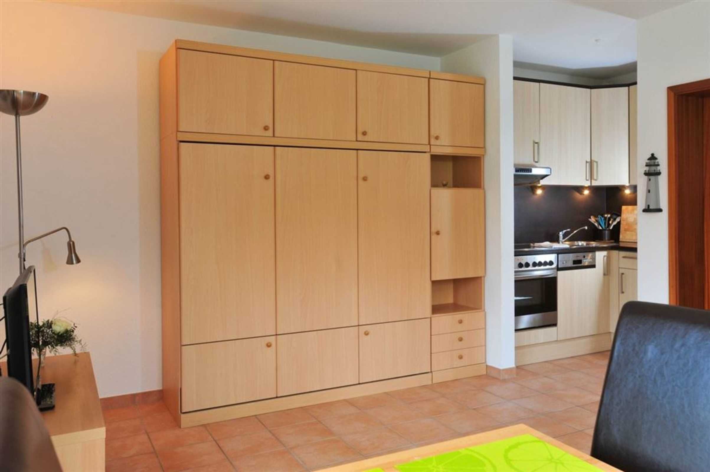 Una cucina compatta con mobili in legno, un fornello e un'area pranzo con tavolo e sedie.