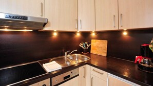 A modern kitchen with wooden cabinets, a stainless steel sink, and a built-in oven.
