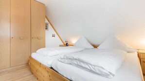A bedroom with a wooden bed, a wardrobe, and a bedside table with a lamp. - House section 8 Greetje (ID 261) (Sankt Peter-Ording)
