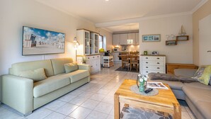 Un salon moderne comprenant un canapé, une table basse et un coin repas avec des chaises et une table.