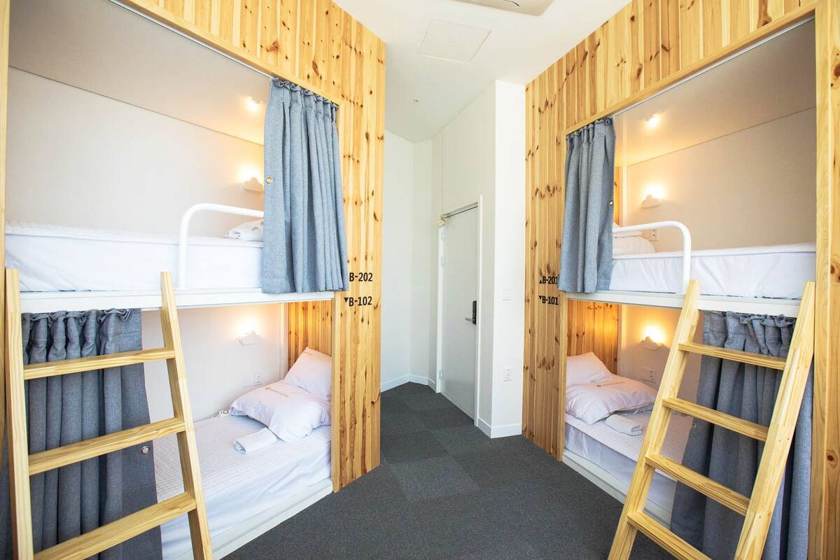 A dormitory room with bunk beds, wooden paneling, and a carpeted floor.