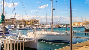 Un port de plaisance où sont amarrés de nombreux bateaux, un ciel dégagé et des bâtiments en arrière-plan.