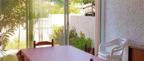 A dining area with a table and chairs, a ceiling fan, and a view through a glass door.