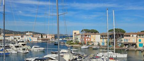 A marina with multiple boats docked, surrounded by buildings with Mediterranean architecture.